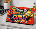 A rectangular cutting board with a vibrant cartoon graphic sits on a kitchen countertop. The graphic features a red background with the text 'Chop It You CUNT!' in bold multicolored letters, alongside cartoon illustrations of an angry carrot holding a knife and an angry onion giving a middle finger.