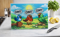 A rectangular glass cutting board, depicting 3 colourful birds, sat in a countryside setting, all saying the word CUNT! The cutting board sits on a marble kitchen worktop alongside a knife and freshly cut lemons