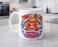 A white ceramic coffee mug with a colourful cartoon bear graphic and the text 'DON'T CARE YOU'RE A CUNT' sitting on a grey kitchen countertop.