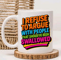 A white ceramic mug with a colorful text graphic reading 'I REFUSE TO ARGUE WITH PEOPLE THAT SHOULD'VE BEEN SWALLOWED' in orange, blue, green, and pink lettering, styled on a wooden coaster with a woven basket in the background.