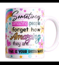 A white ceramic mug with a colorful printed message that reads, 'Sometimes amazing people forget how amazing they are.