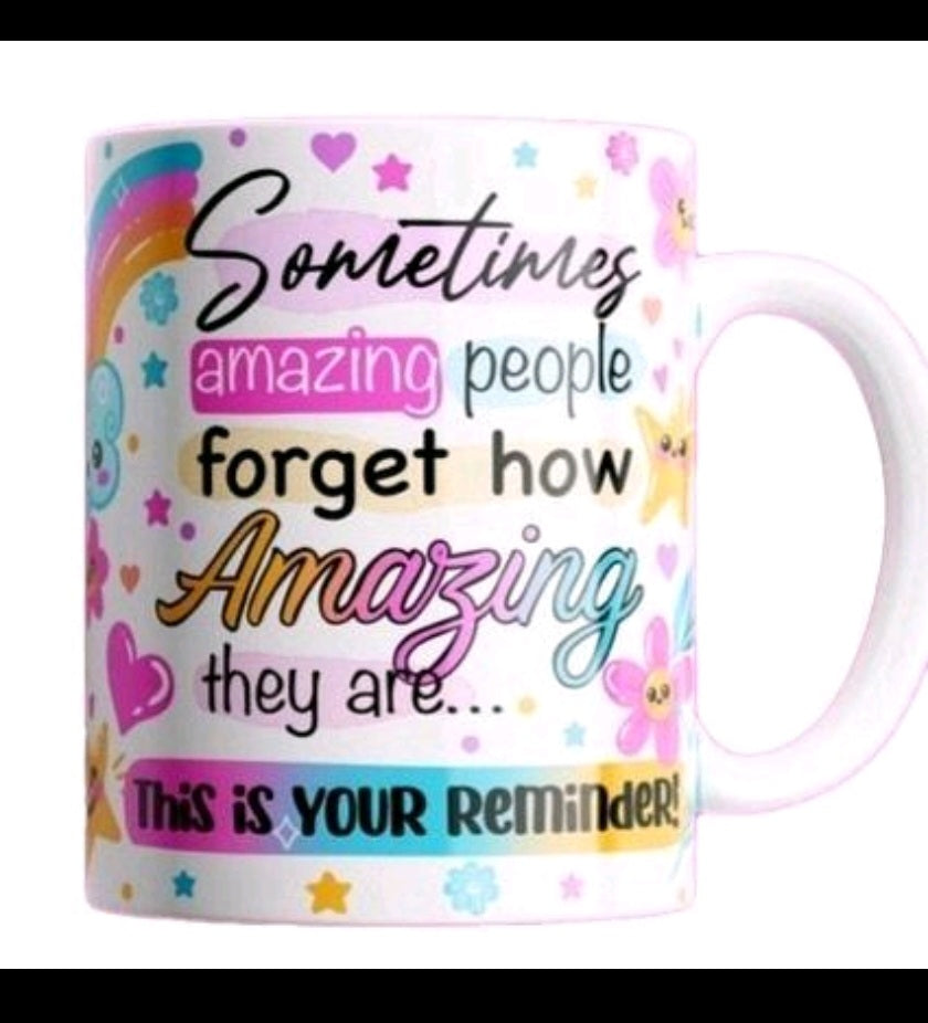 A white ceramic mug with a colorful printed message that reads, 'Sometimes amazing people forget how amazing they are.