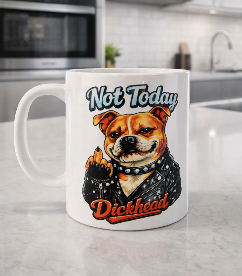 A white ceramic coffee mug with a cartoon bulldog wearing a leather jacket and the text 'Not Today Dickhead' printed on it, sitting on a light grey marble kitchen countertop with a blurred kitchen background.