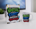 A white ceramic mug and a matching printed card standing on a white tabletop. The printed design reads, 'IT TAKES A SPECIAL KIND OF CUNT TO HAVE A BIRTHDAY IN DECEMBER' in bold green, blue, red, and black graffiti-style lettering.